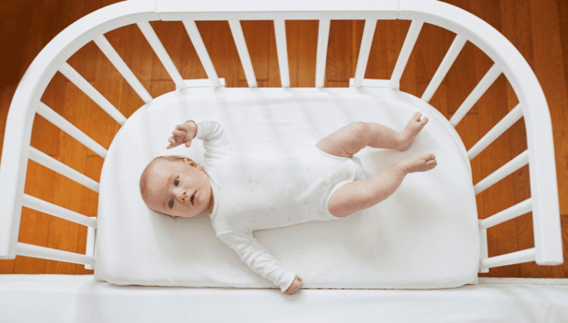 baby-lying-on-a-white-bedside-bassinet