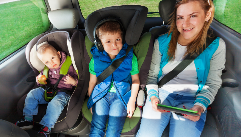 three-kids-of-different-ages-sitting-in-the-backseat-of-a-car