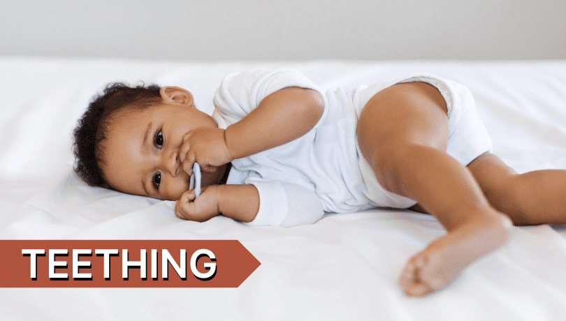 brown-baby-lying-on-his-side-chewing-on-a-toy