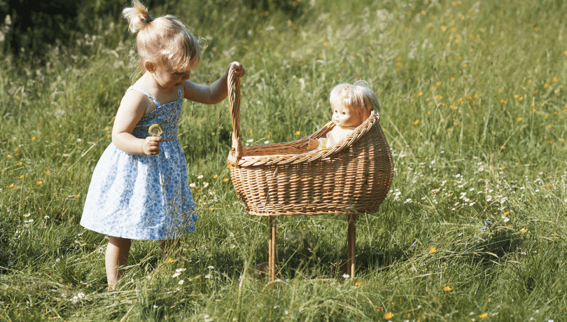 little-girl-playing-with-doll-kept-in-a-bassinet