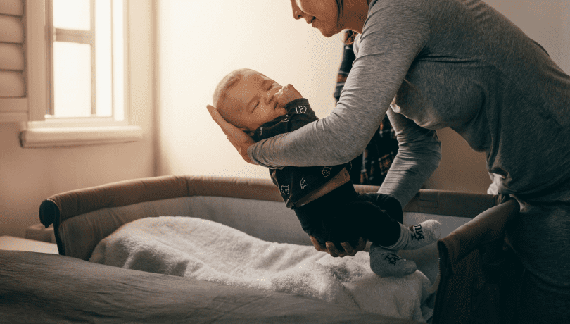 mother-placing-sleeping-baby-on-a-bedside-bassinet