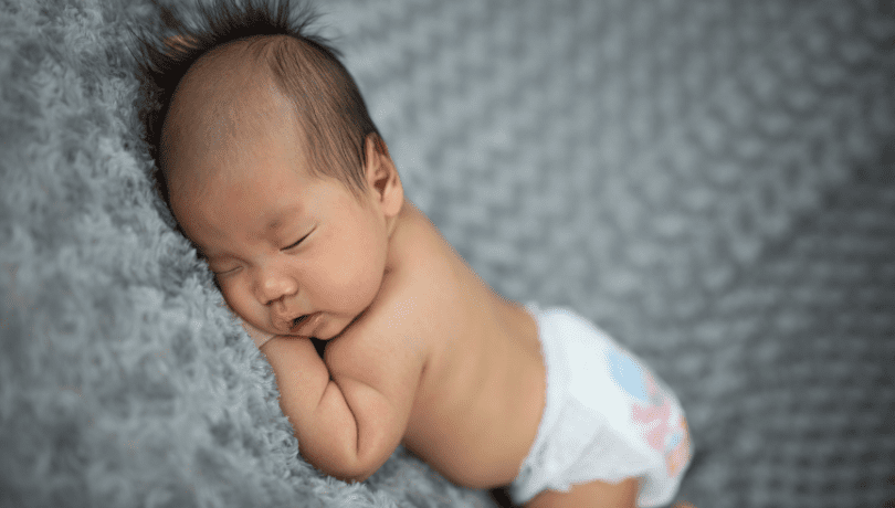 6-week-old-baby-sleeping-on-a-grey-blanket