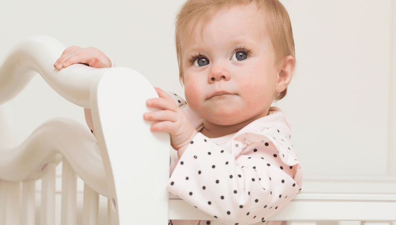 9-month-old-baby-girl-looking-up-from-her-crib