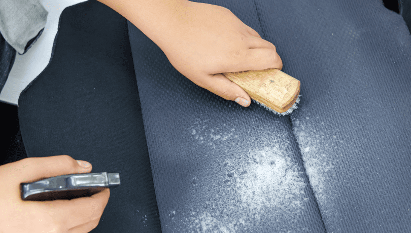 cleaning-a-car-seat-with-a-brush-and-bottle-spray