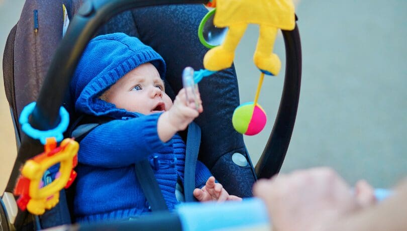 baby-on-stroller-playing-with-toys