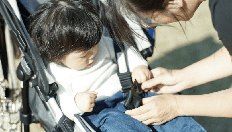 mother-fastening-baby-boy-in-stroller