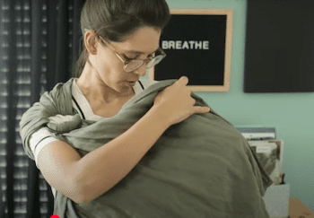 Illustration of a mother breastfeeding her baby in a front-facing baby wrap.